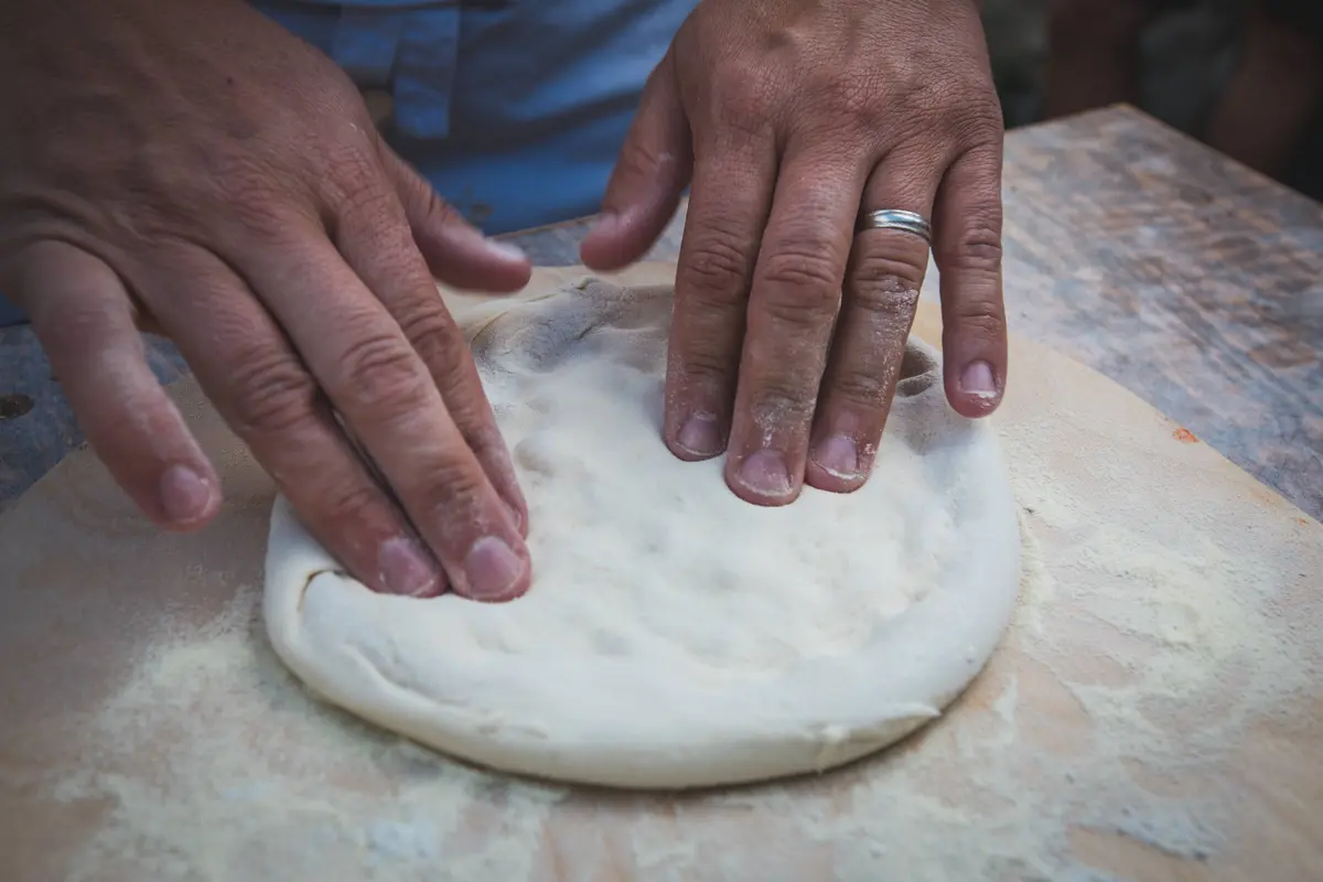 Pizza dough being shaped by hand